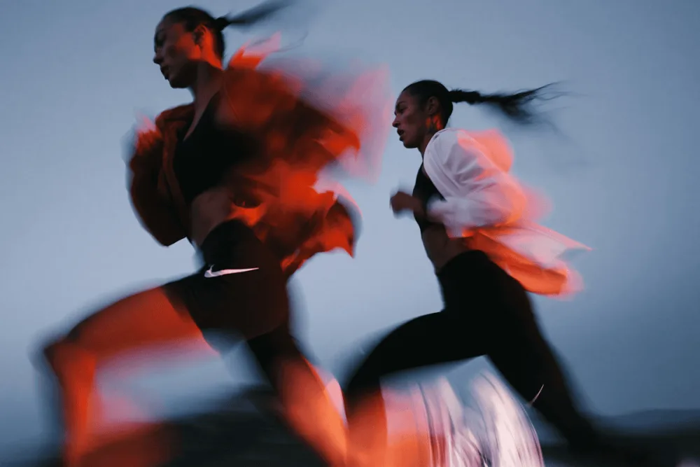 Two runners in motion with red light trails